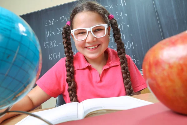 Lycklig skolflicka framför svarta tavlan — Stockfoto