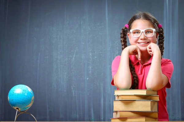 Happy school girl in front of the blackboard