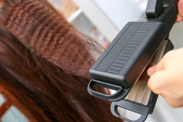 Close up of stylist hands with styling iron straightening woman — Stock Photo, Image