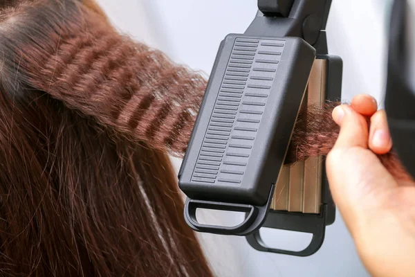 Close up of stylist hands with styling iron straightening woman — Stock Photo, Image