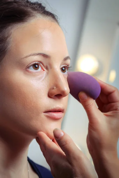 Stichting door sponge op gezicht voor make-up toe te passen — Stockfoto