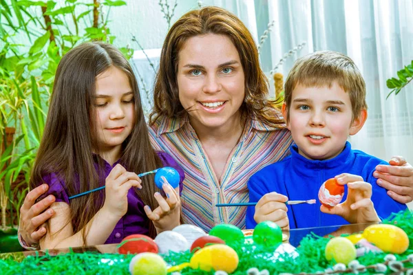 Mutter und ihre Kinder bemalen Ostereier — Stockfoto