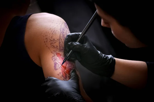 Tatuaje femenino artista haciendo tatuaje en el brazo de un hombre —  Fotos de Stock