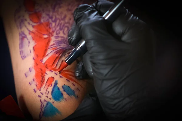 Женщина-татуировщица делает татуировку на руке мужчины — стоковое фото