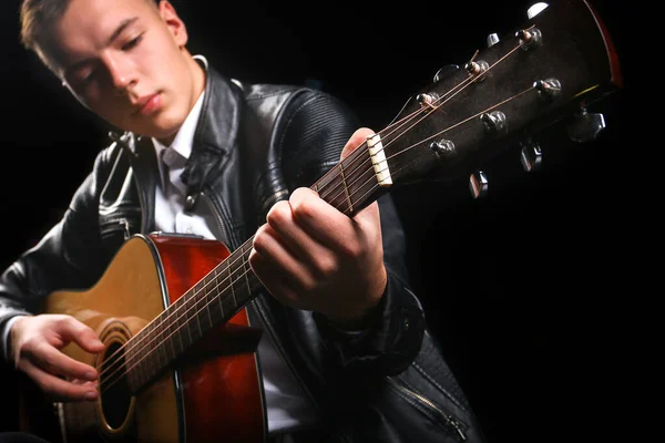 Young men playing the guitar with black background