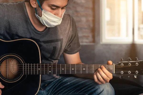 person wearing mask against virus in quarantine, playing music at home