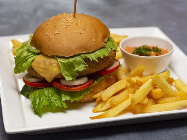 Taze marul, domates, soğan ve peynirli hamburger ve patates kızartması.