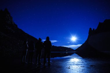 Dört kişi ay ışığını ve Bariloche 'deki Frey Dağı' nın tepesindeki göldeki yansımasını düşünüyordu (Patagonya Arjantin).
