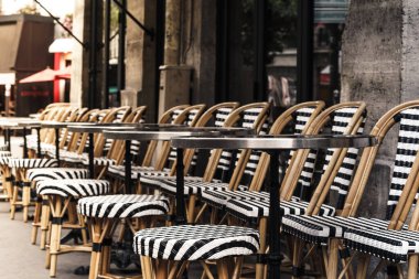 Siyah beyaz sandalyeleri ve kaldırımda sıralanmış masaları olan Paris kafesi.