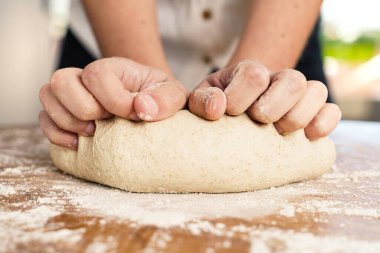 Kadın elleriyle ekmek hamuru yoğuruyor.