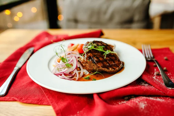 Sebzeli, beyaz tabakta etli biftek.