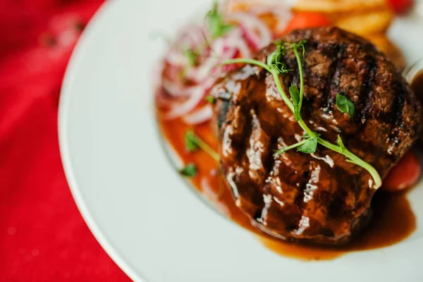 Sebzeli, beyaz tabakta etli biftek.