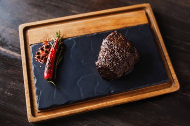 Biberli, sulu biftek. Karanlık bir arka planda. Masa manzaralı bir karatahtanın üstünde.