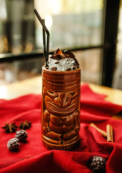  Kırmızı arka plan putperest heykellerinde buzlu ve pipetli kokteyl.