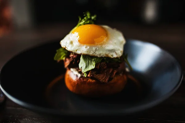  Siyah tabakta yumurta ve peynirli güzel bir hamburger.