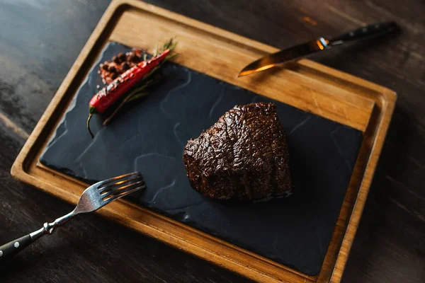 Biberli, sulu biftek. Karanlık bir arka planda. Masa manzaralı bir karatahtanın üstünde.