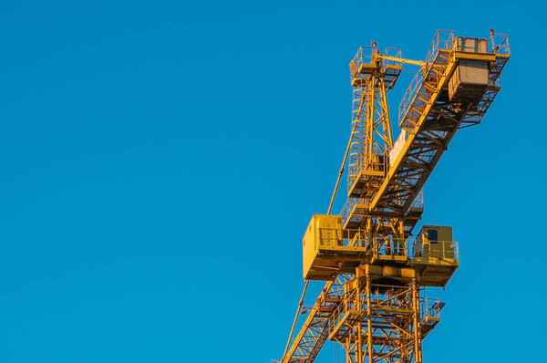 Construction crane on a background of blue sky. Copy space.