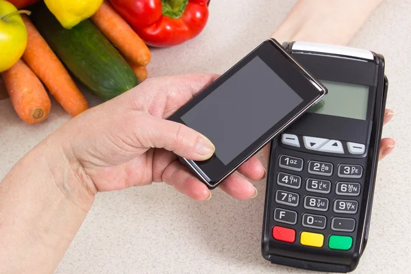 Mano de mujer mayor usando terminal de pago con teléfono móvil, pagando por las compras — Foto de Stock