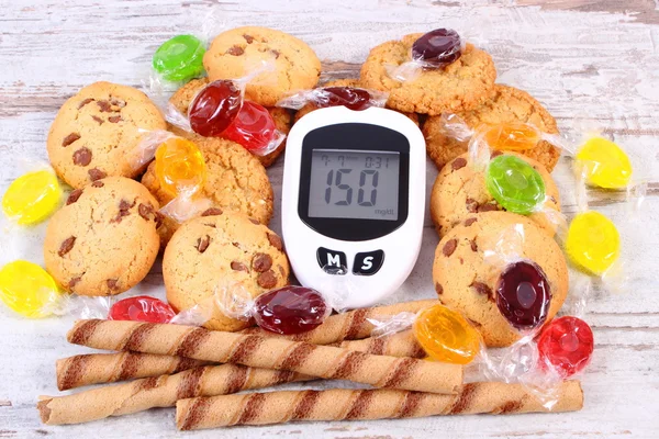 Glucometer y caramelos coloridos con galletas, diabetes, reducción de comer dulces — Foto de Stock
