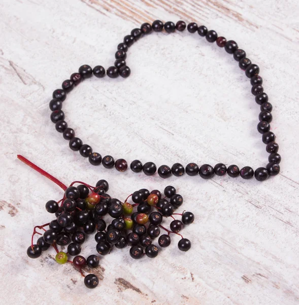Heart of fresh elderberry on old wooden background, symbol of love — Stock Photo, Image