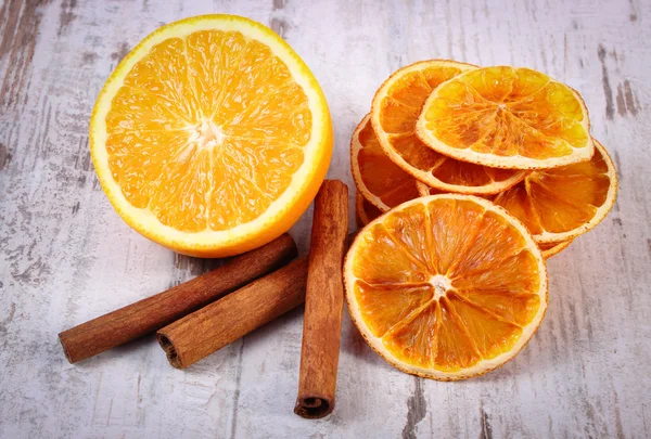 Сушеный и свежий апельсин с корицей палочки на старом деревянном фоне — стоковое фото