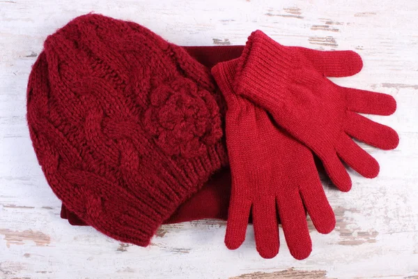 Pair of woolen gloves and cap for woman on old wooden background — 图库照片