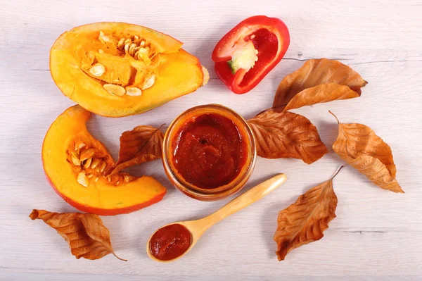 Sauce of pumpkin in glass jar and autumnal leaves on wooden table — Φωτογραφία Αρχείου