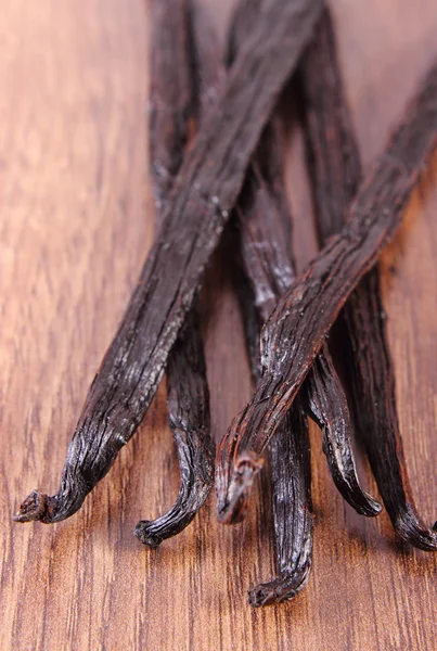 Fragrant vanilla sticks on wooden surface plank