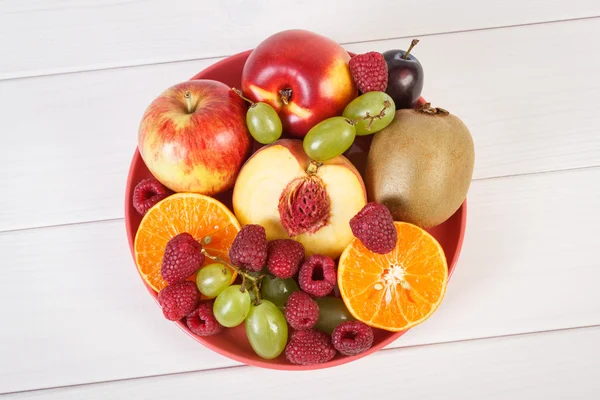 Свежие спелые фрукты на тарелке лежат на белых досках — стоковое фото