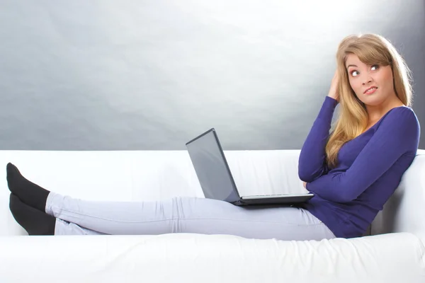 Беспокойная женщина сидит на диване и смотрит на ноутбук, современные технологии — стоковое фото