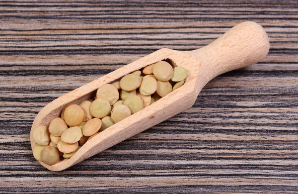 Heap of green lentil with spoon on wooden background — Stock Photo, Image