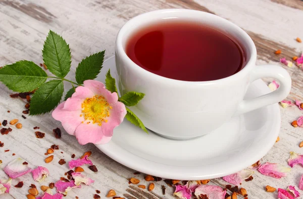Kopje thee met wild rose bloem op oude rustieke houten achtergrond — Stockfoto