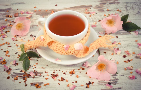 Vintage foto, xícara de chá com flor de rosa selvagem no velho fundo de madeira rústica — Fotografia de Stock
