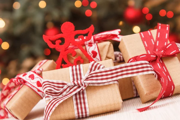 Inslagna gåvor och julgran med ljus i bakgrunden — Stockfoto