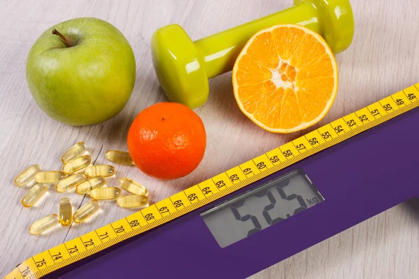 Digital scale with tape measure, dumbbells, tablets, fruits, slimming concept — Stock Photo, Image