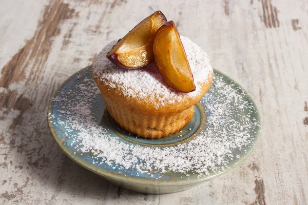Muffin appena sfornati con prugne e zucchero a velo sul piatto, delizioso dessert — Foto Stock