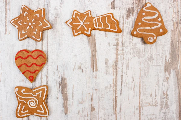 Fresh baked decorated gingerbread on old wooden background, christmas time — Stock Photo, Image