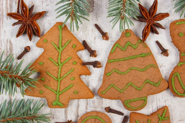 Decorated gingerbread, spruce branches, spices on old wooden background, christmas decoration — Stock Photo, Image