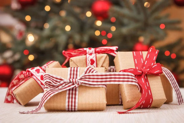 Inslagna gåvor och julgran med ljus i bakgrunden — Stockfoto