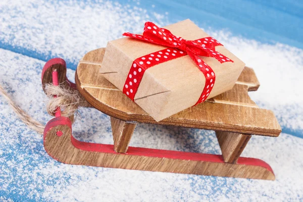 Slitta di legno e regalo avvolto per Natale o altra celebrazione su tavole innevate — Foto Stock