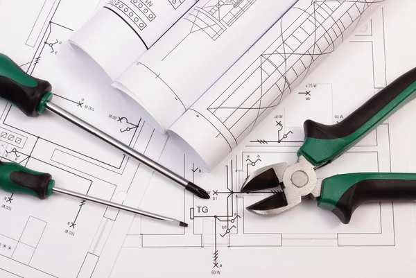 Rolos de diagramas e ferramentas de trabalho no desenho de construção elétrica de casa — Fotografia de Stock