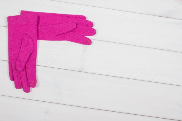 Pink gloves for woman on boards, clothing for autumn or winter, copy space for text
