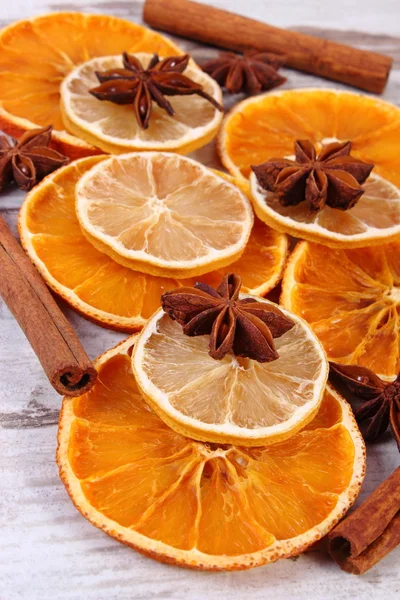 Slices of dried lemon, orange and spices on old wooden background — Stock Photo, Image