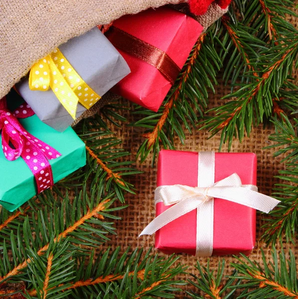 Загорнуті подарунки в джутовий мішок на Різдво або інші урочистості та гілки ялини — стокове фото