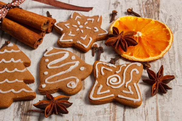 Fresh baked decorated gingerbread with spices on old wooden background, christmas time — Stock Photo, Image