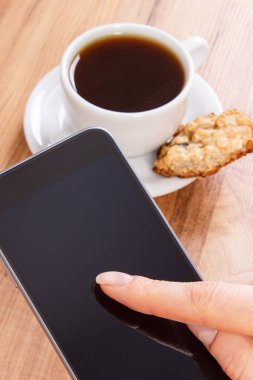 Cep telefonu, yulaf ezmeli kurabiye ve kahve kullanan kadın eli