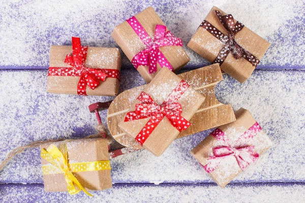 Regalos de trineo de madera y envueltos para Navidad u otra celebración en tablas nevadas — Foto de Stock