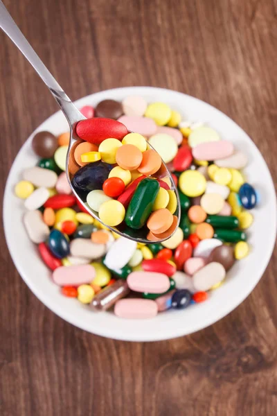 Çay kaşığı ve yığın renkli tıbbi kapsül içinde geçmiş, sağlık kavramı tıbbi ilaçlar