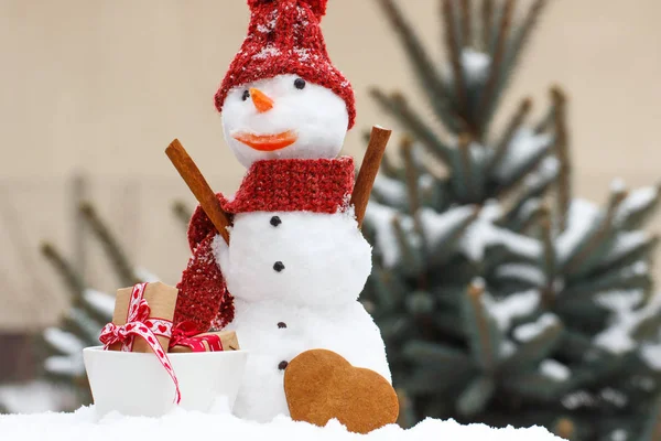 Snögubbe med presenter till jul eller Valentine och pepparkakor på bakgrund av barrträd — Stockfoto