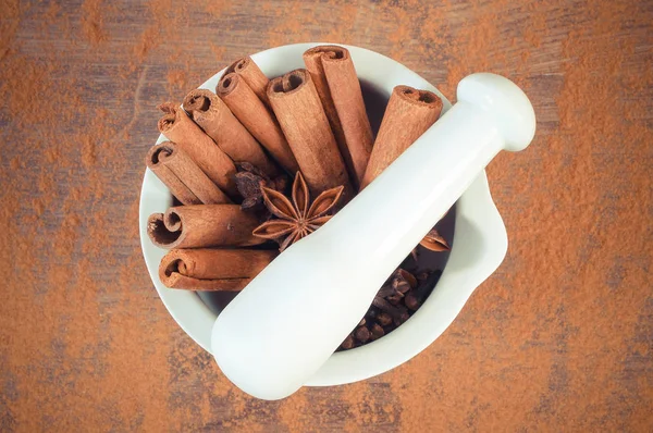 Fragrant anise, cloves, cinnamon sticks in mortar on rustic board — Stock Photo, Image
